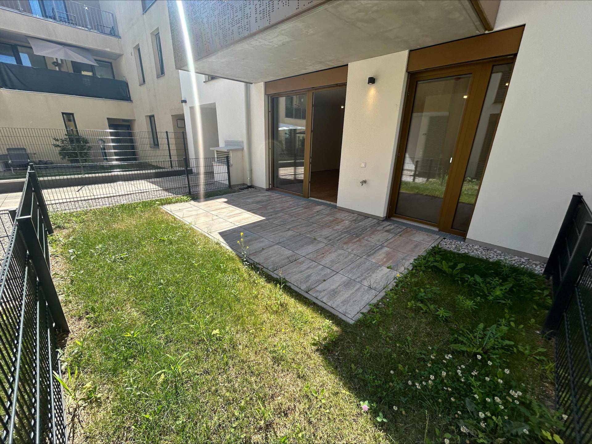 Großzügige Terrasse mit Steinplatten und angrenzendem Gartenbereich, ideal für Erholung im Freien.
