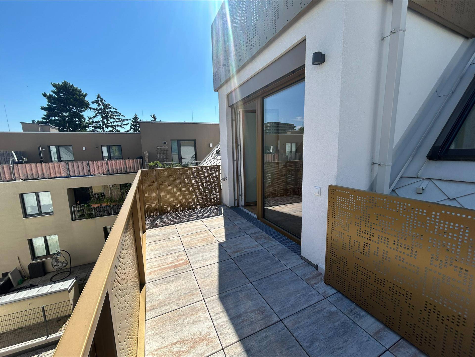 Sonniger Außenbereich mit modernen Fliesen und dekorativen Metallgeländern, ideal zum Entspannen.