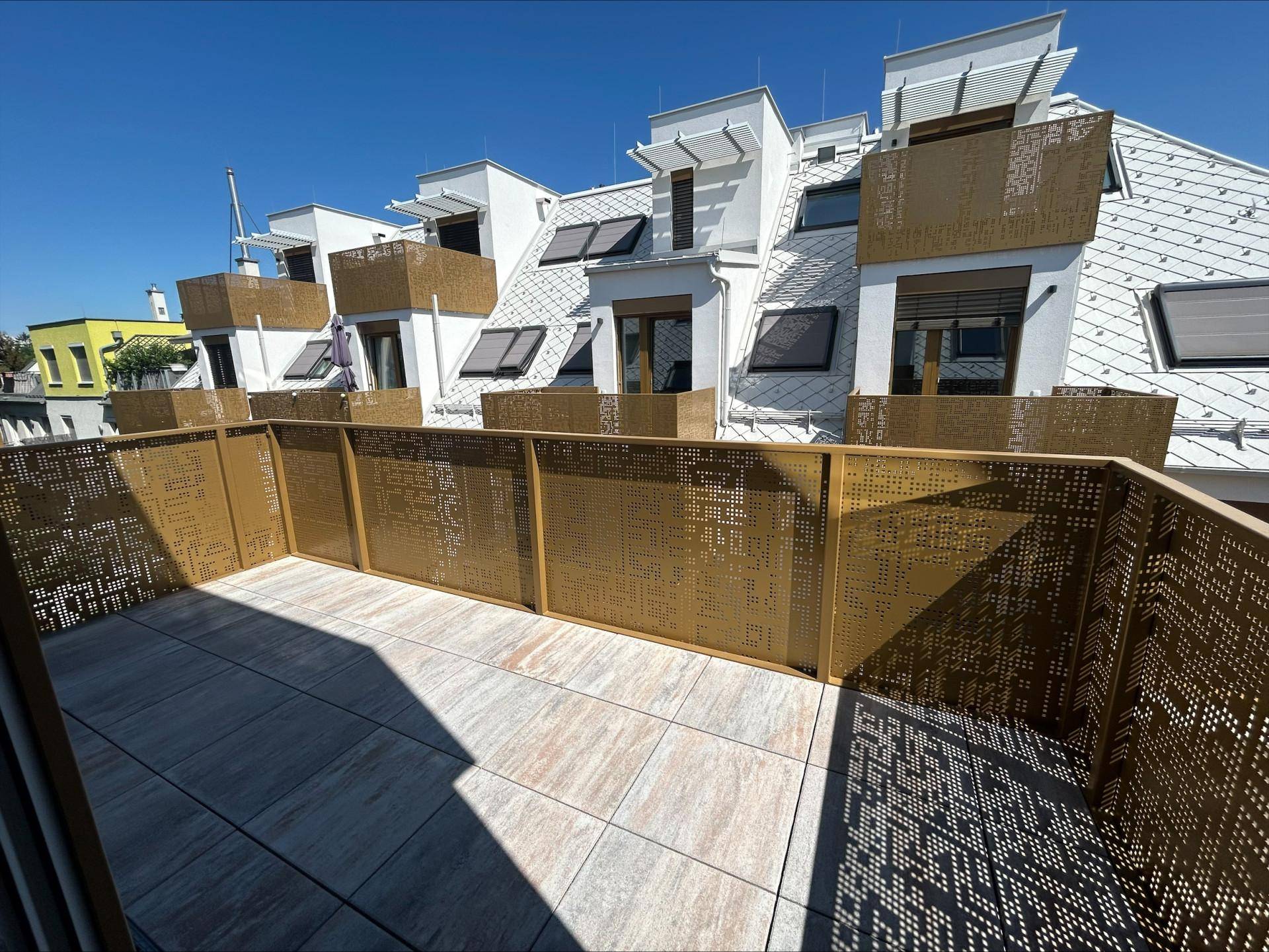 Weitläufige Terrasse mit Blick auf die moderne Architektur des Gebäudes und weitere Dachterrassen.