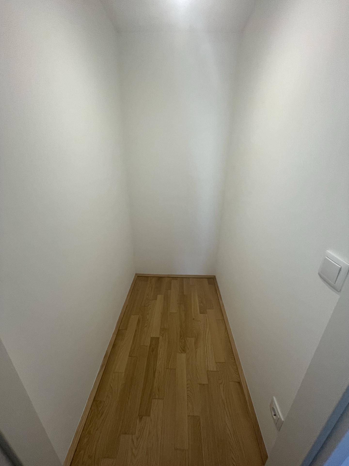 Kleiner, leerer Raum mit Holzboden, ideal als Abstellraum oder begehbarer Kleiderschrank.