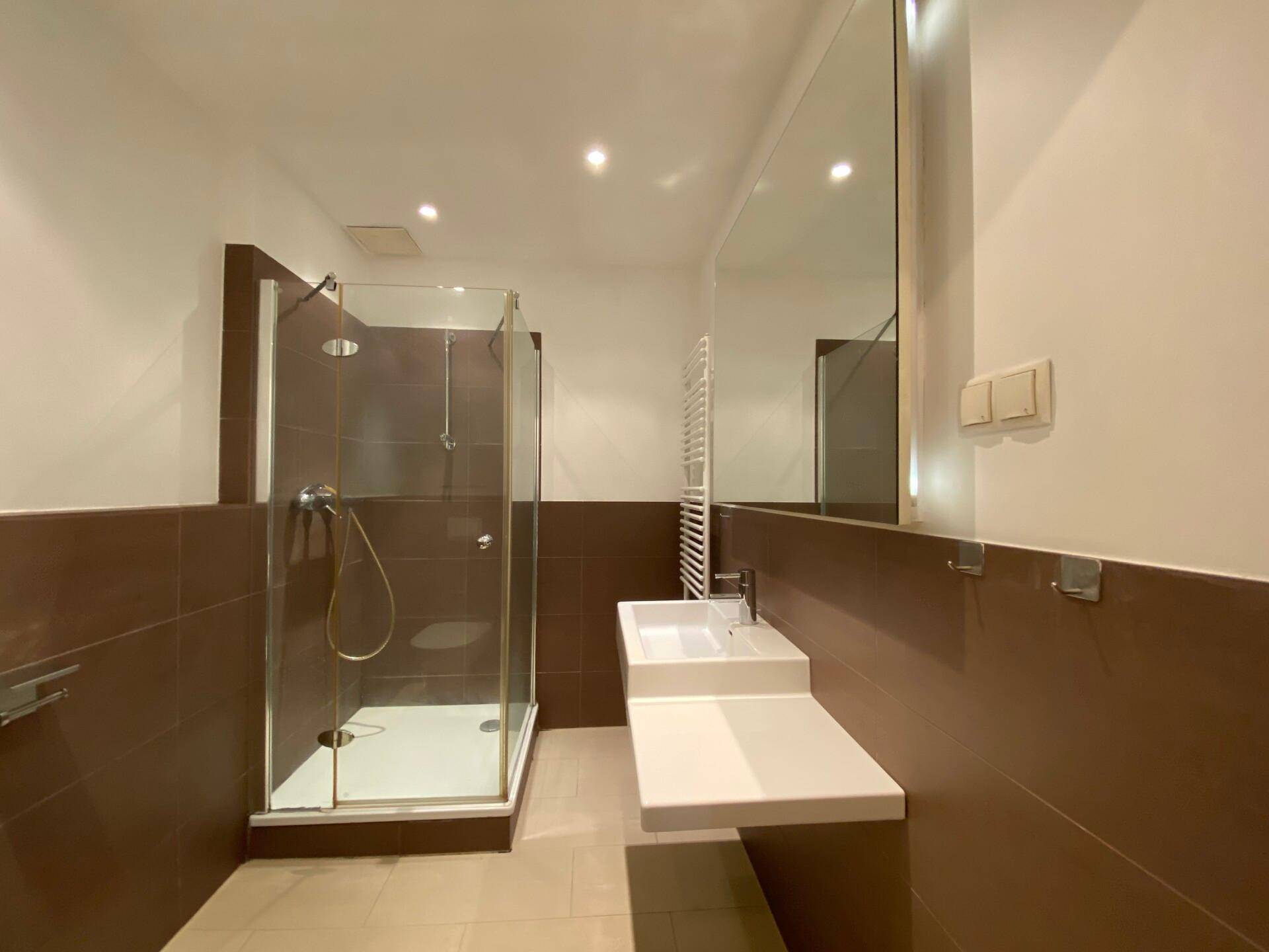 Modernes Badezimmer mit großer Duschkabine, Einzelwaschbecken und beheiztem Handtuchhalter.