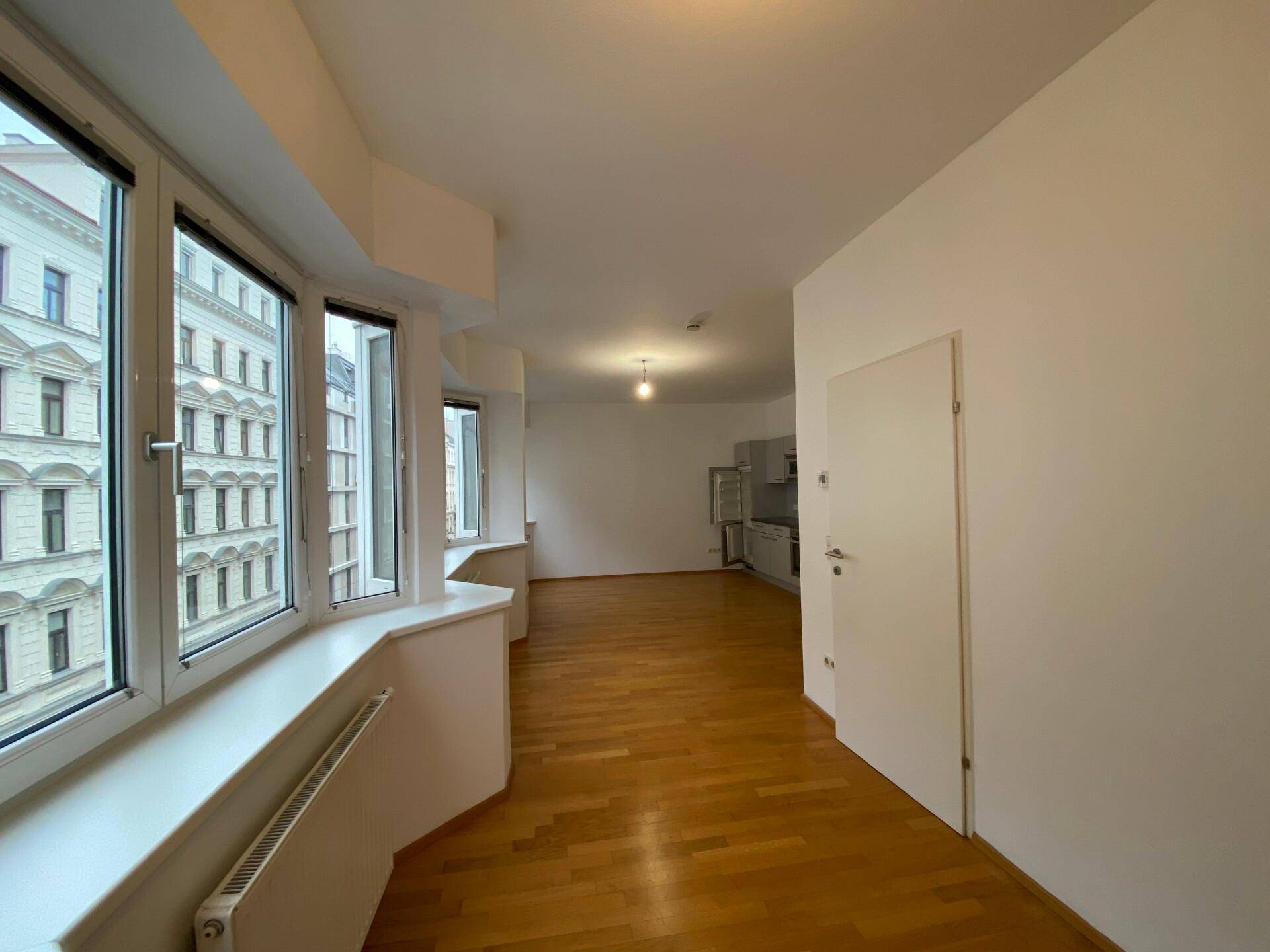 Geräumiger Wohnbereich mit Parkettboden und einer langen Fensterfront, die viel Licht spendet.
