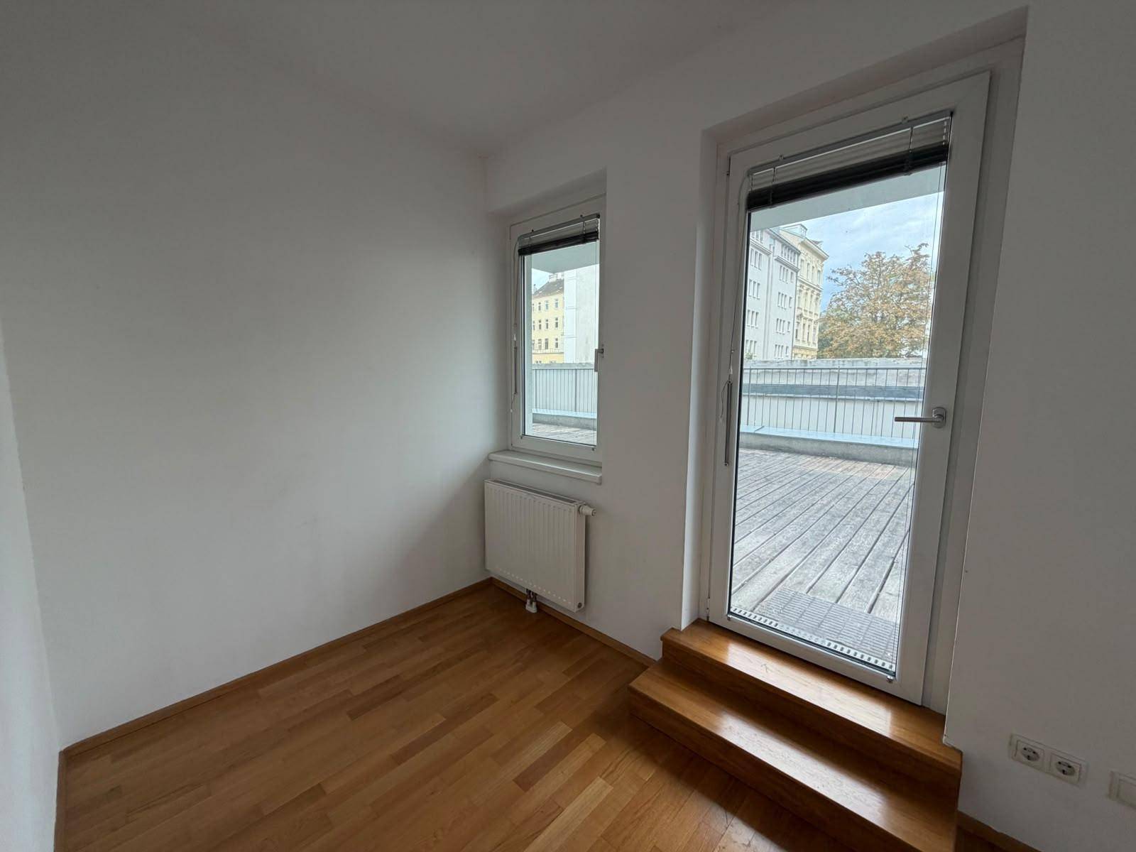 Helles Schlafzimmer mit Parkettboden und direktem Zugang zur Außenterrasse, bietet viel Tageslicht.