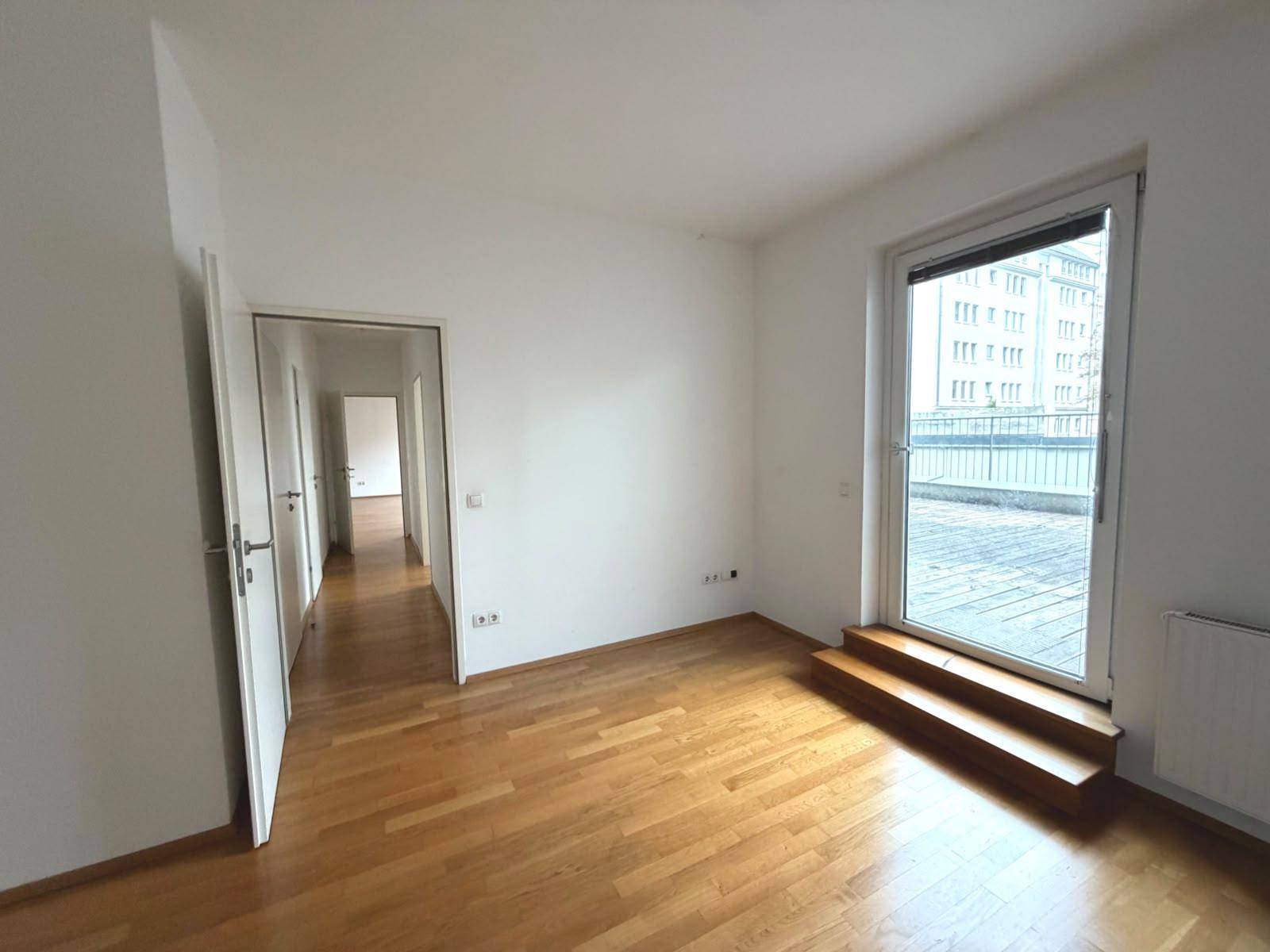 Helles Schlafzimmer mit Parkettboden, Terrassenzugang und Verbindung zum Flurbereich, gut geschnitten.