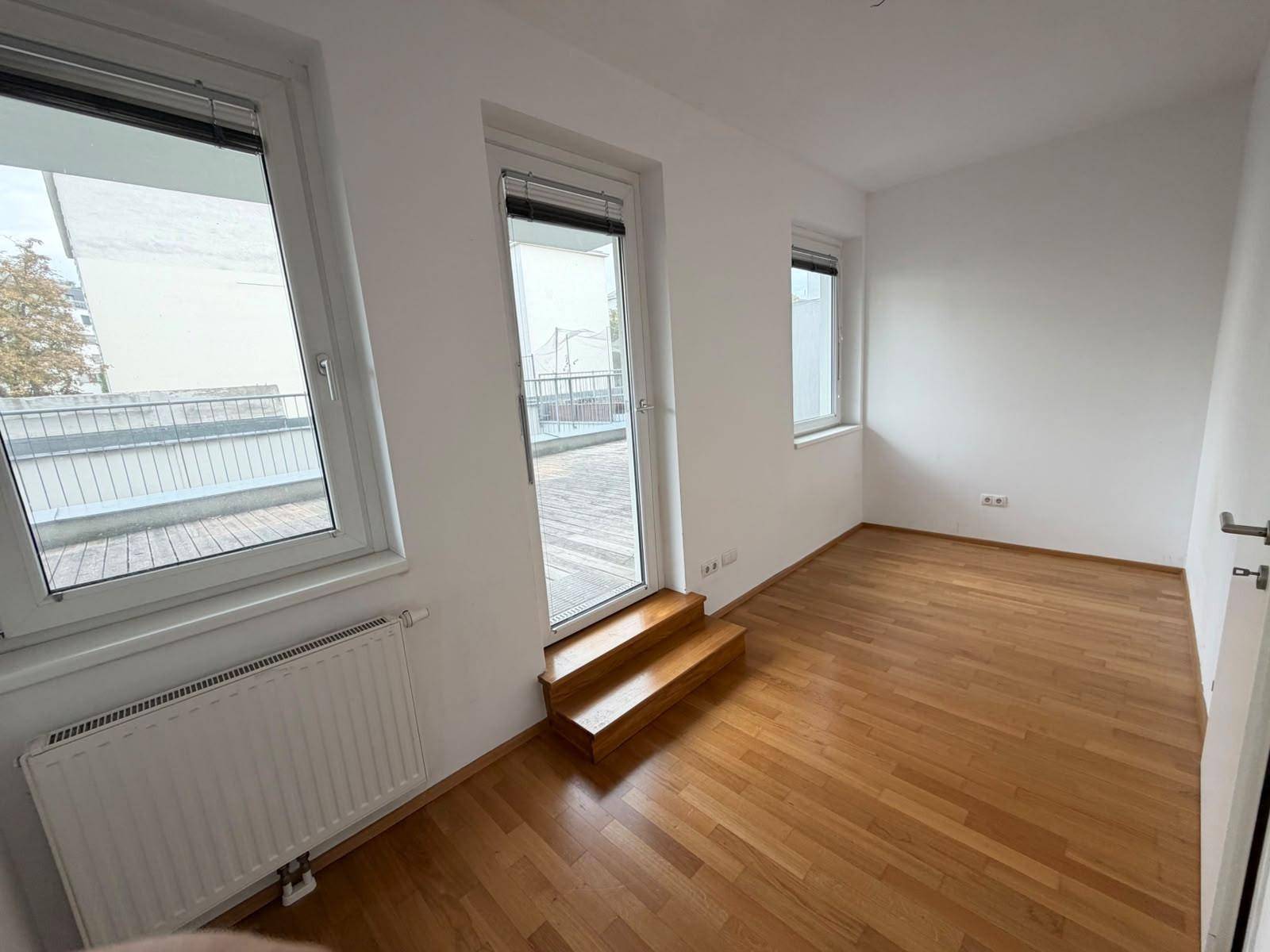 Geräumiges Schlafzimmer mit Parkettboden und großem Fenster sowie Terrassenzugang, sehr hell.