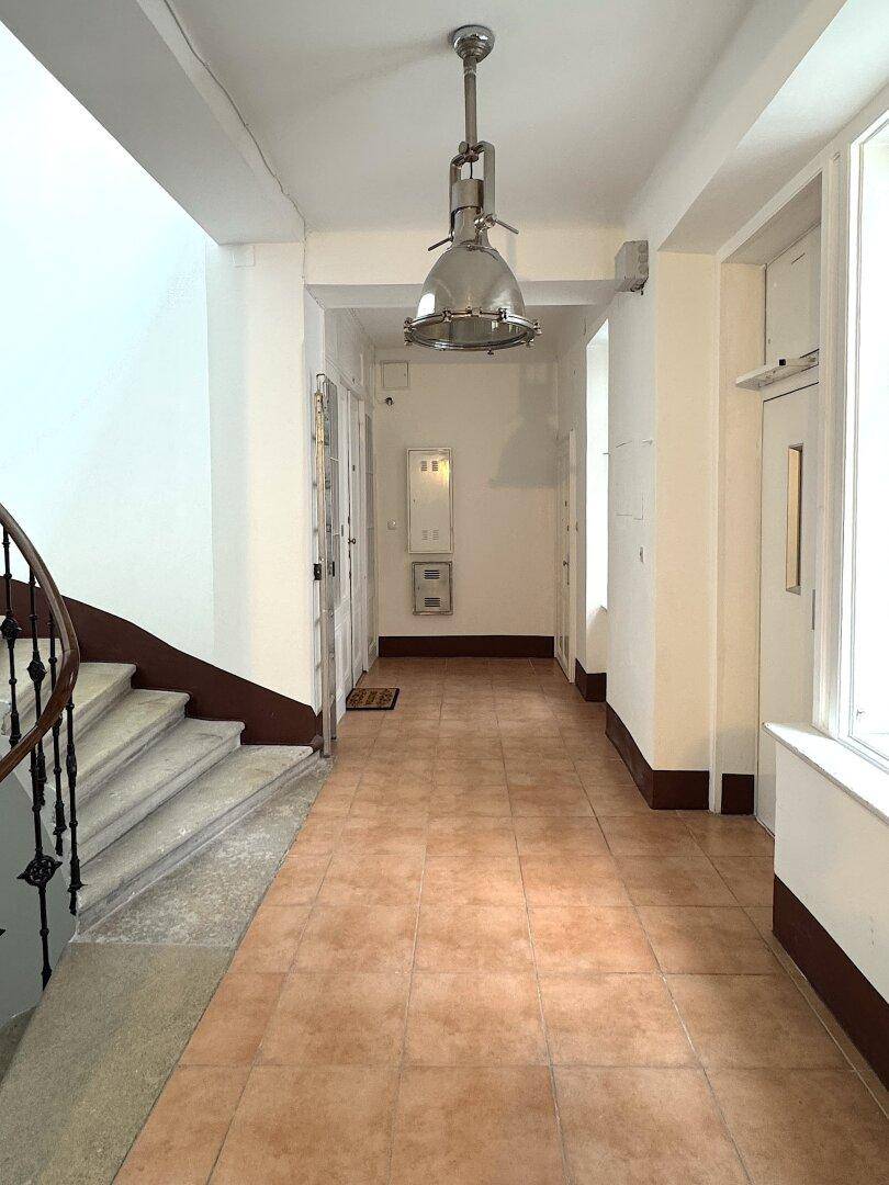 Heller Treppenhausflur mit gefliestem Boden und eleganter Wendeltreppe.