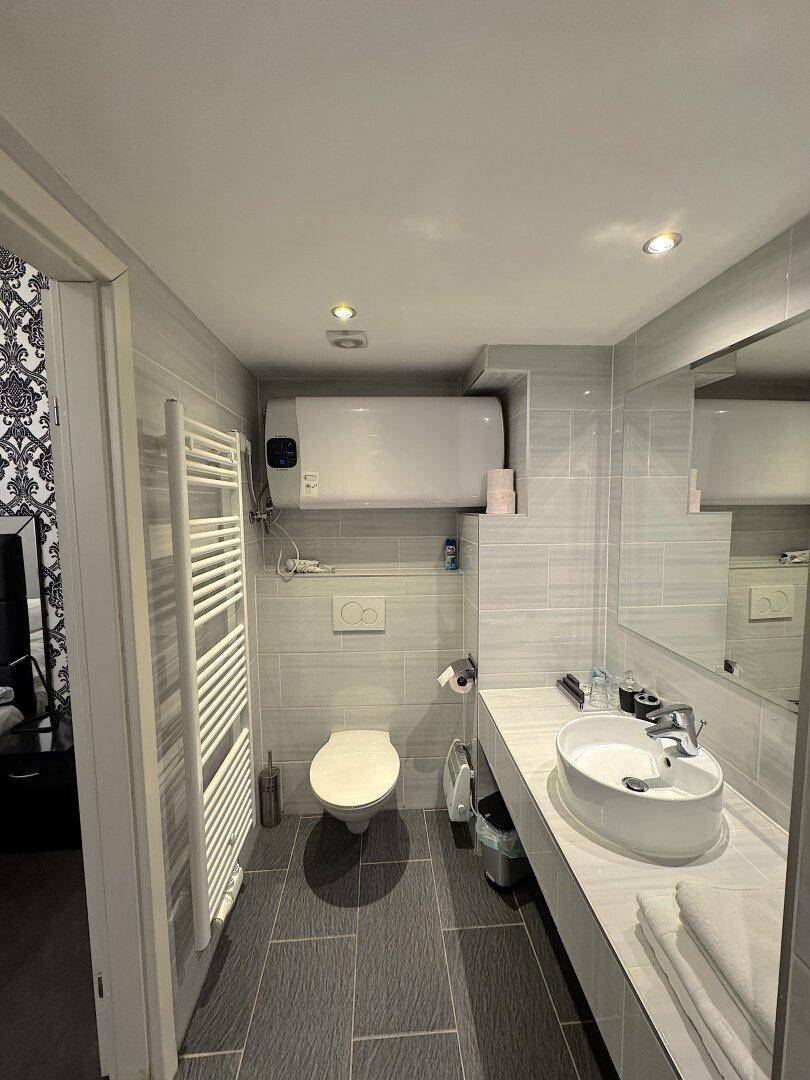 Badezimmer mit modernem Waschbecken, wandhängender Toilette und beheiztem Handtuchhalter.