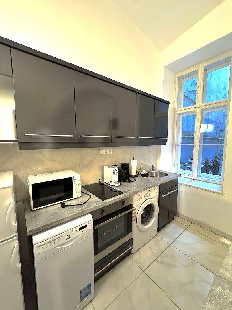 Funktionale Küchenzeile mit Einbaugeräten, Spüle und Fenster für Tageslicht.