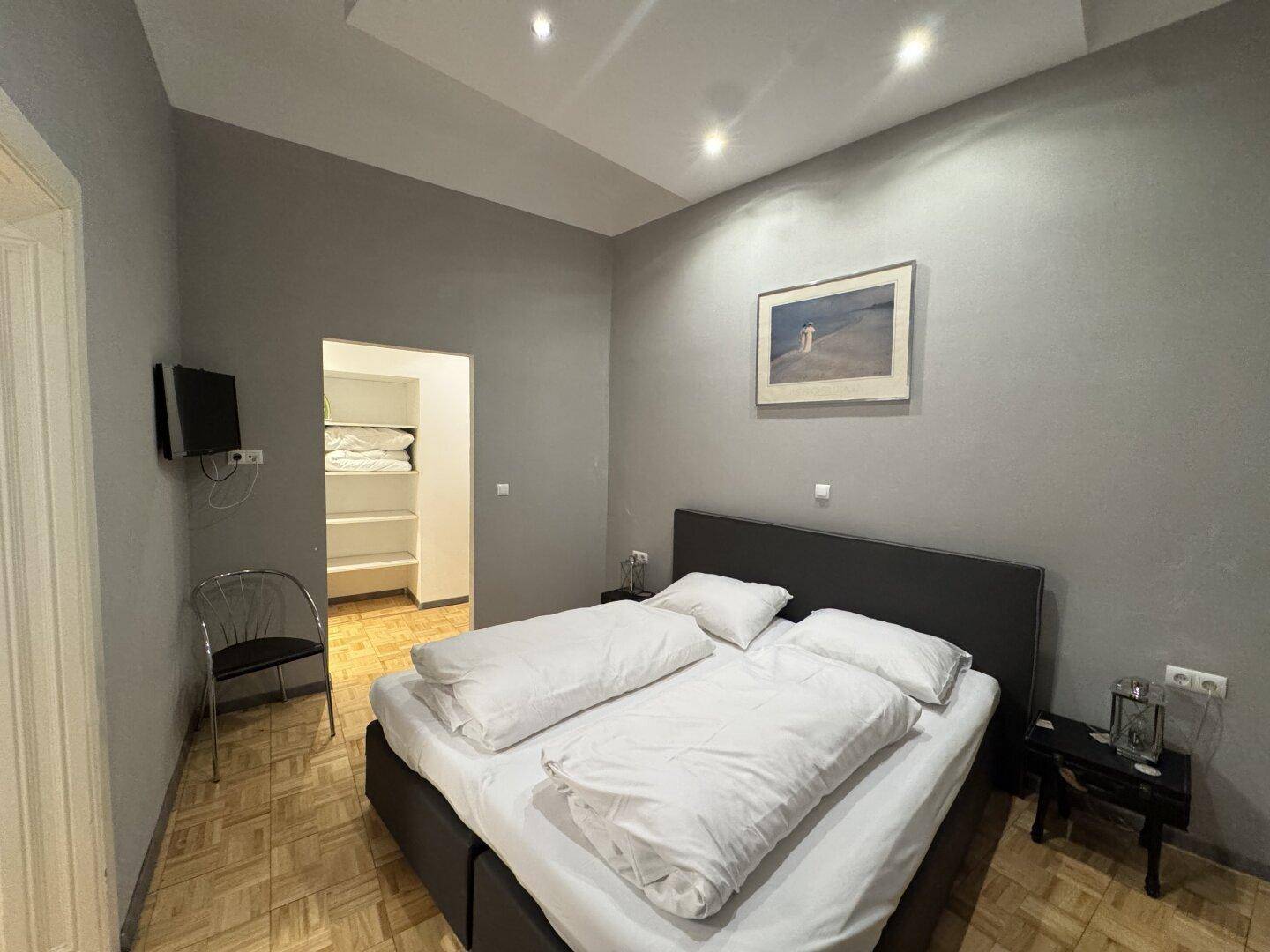 Gemütliches Schlafzimmer mit Doppelbett, Parkettboden und Zugang zum Ankleidezimmer.