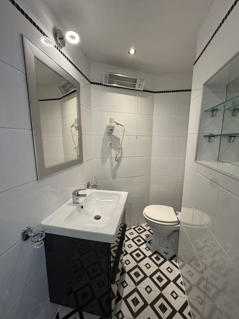 Modernes Badezimmer mit Waschbecken, Toilette und markanten schwarz-weißen Bodenfliesen.