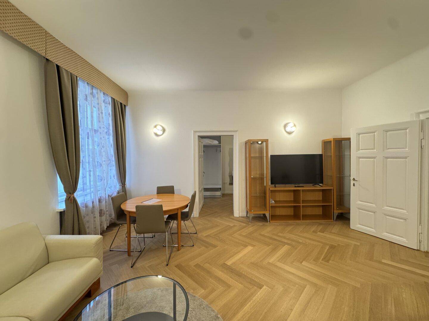 Heller Wohn-Essbereich mit Esstisch, TV-Möbel und Blick auf das Fenster.