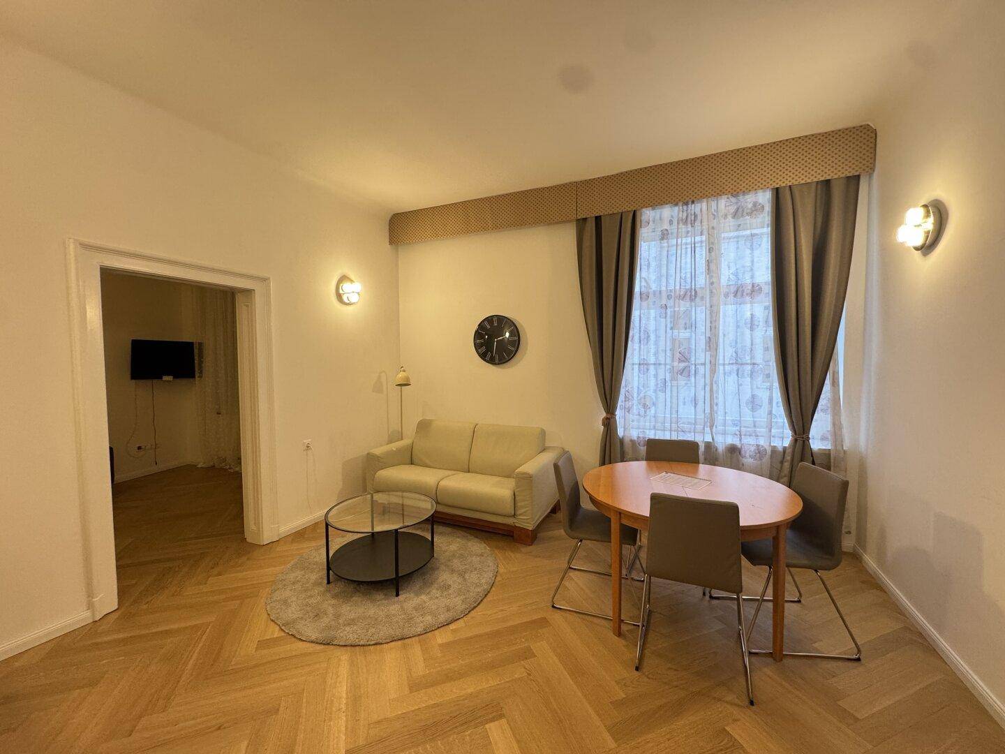 Gemütlicher Wohn-Essbereich mit beigem Sofa, rundem Couchtisch und Esstisch.