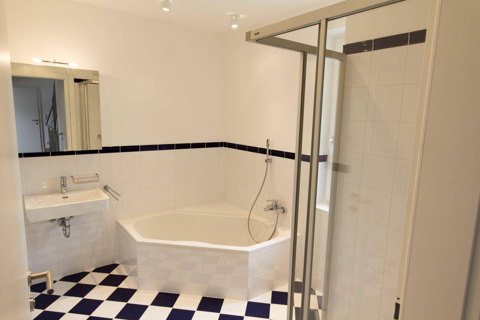 Badezimmer mit Eckbadewanne, Dusche und auffälligem schwarz-weiß kariertem Fliesenboden.