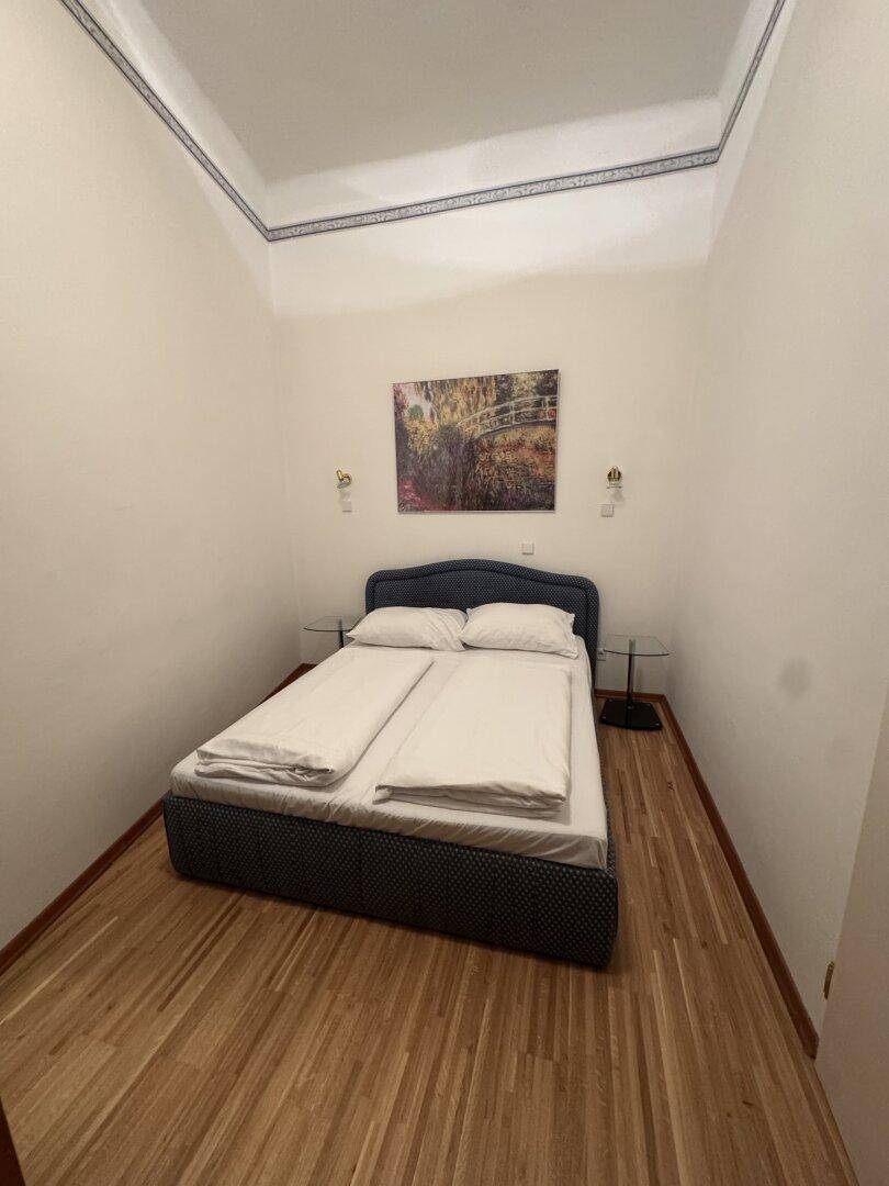 Gemütliches Schlafzimmer mit Doppelbett, Holzparkettboden und einem Bild über dem Bett.