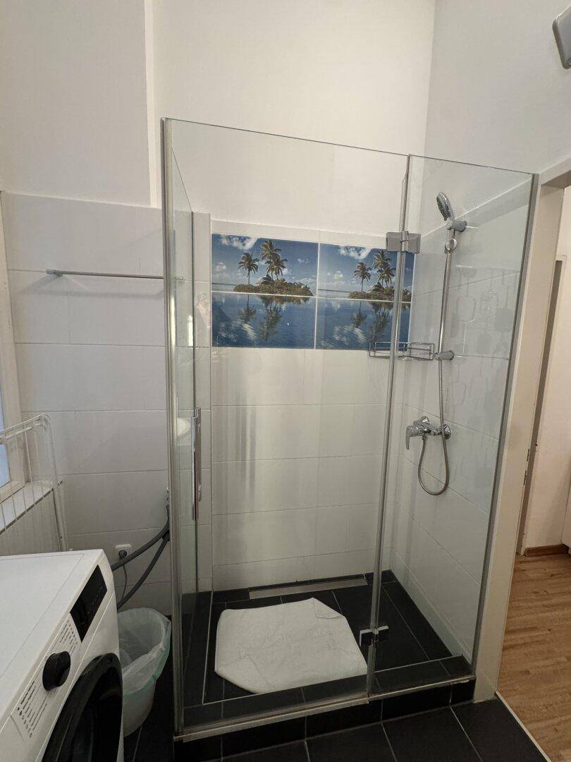 Modernes Badezimmer mit Glasdusche, dunklen Bodenfliesen und weißen Wandfliesen.