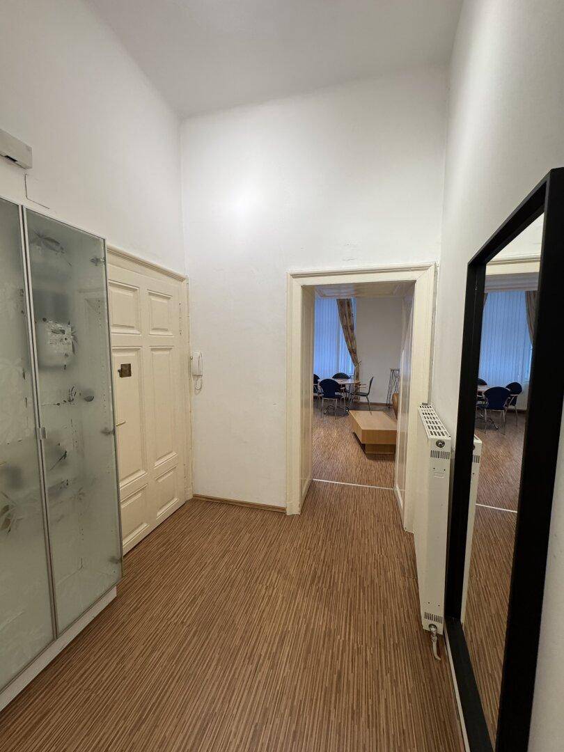 Heller Flur mit Laminatboden, einem großen Spiegel und Zugang zu weiteren Räumen.