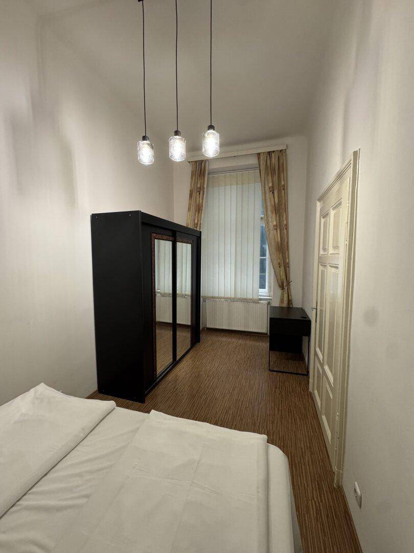 Schlafzimmer mit Doppelbett, Kleiderschrank mit Spiegeltüren und Fenster.