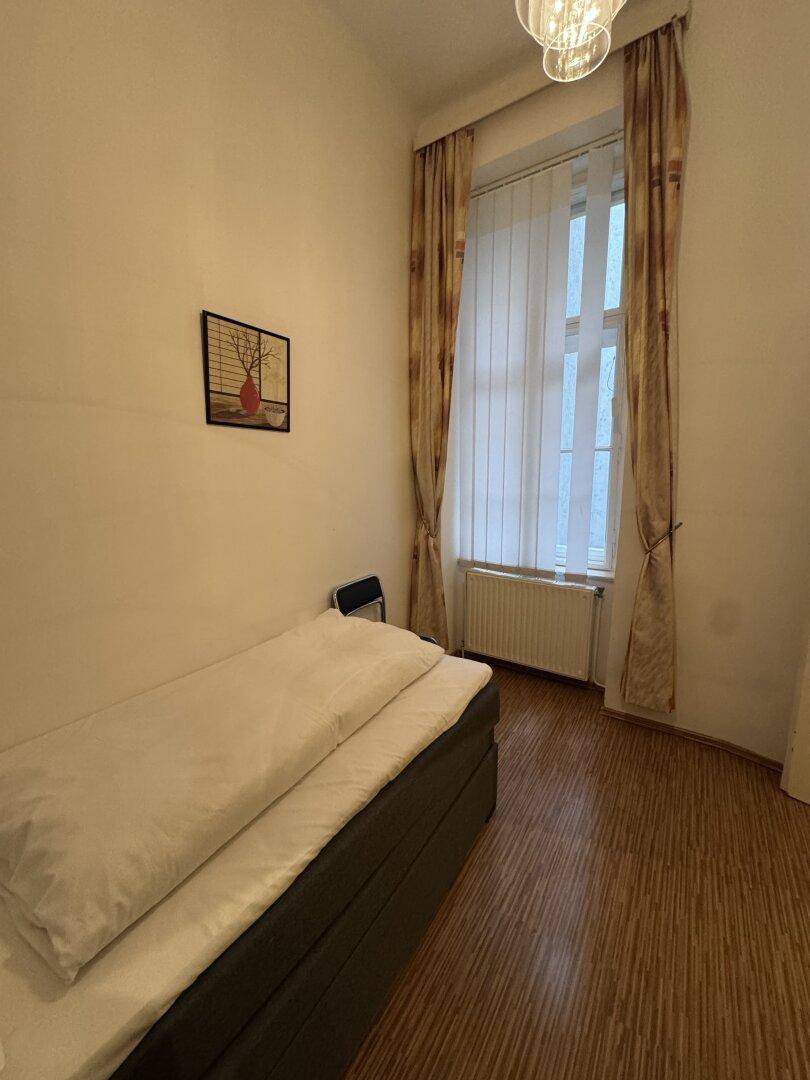 Helles Schlafzimmer mit Einzelbett, Fenster und Vorhängen, ideal für Gäste.