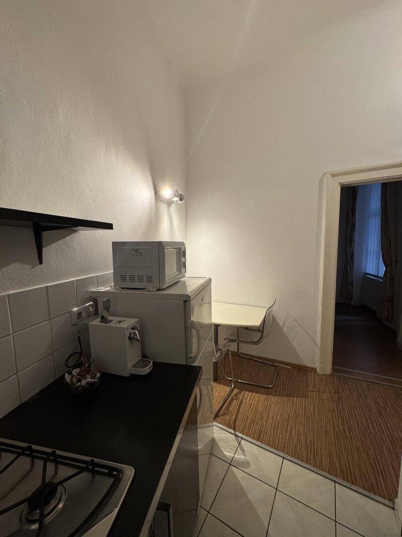 Küche mit kleiner Essecke, Mikrowelle und Kühlschrank, verbunden mit Wohnbereich.