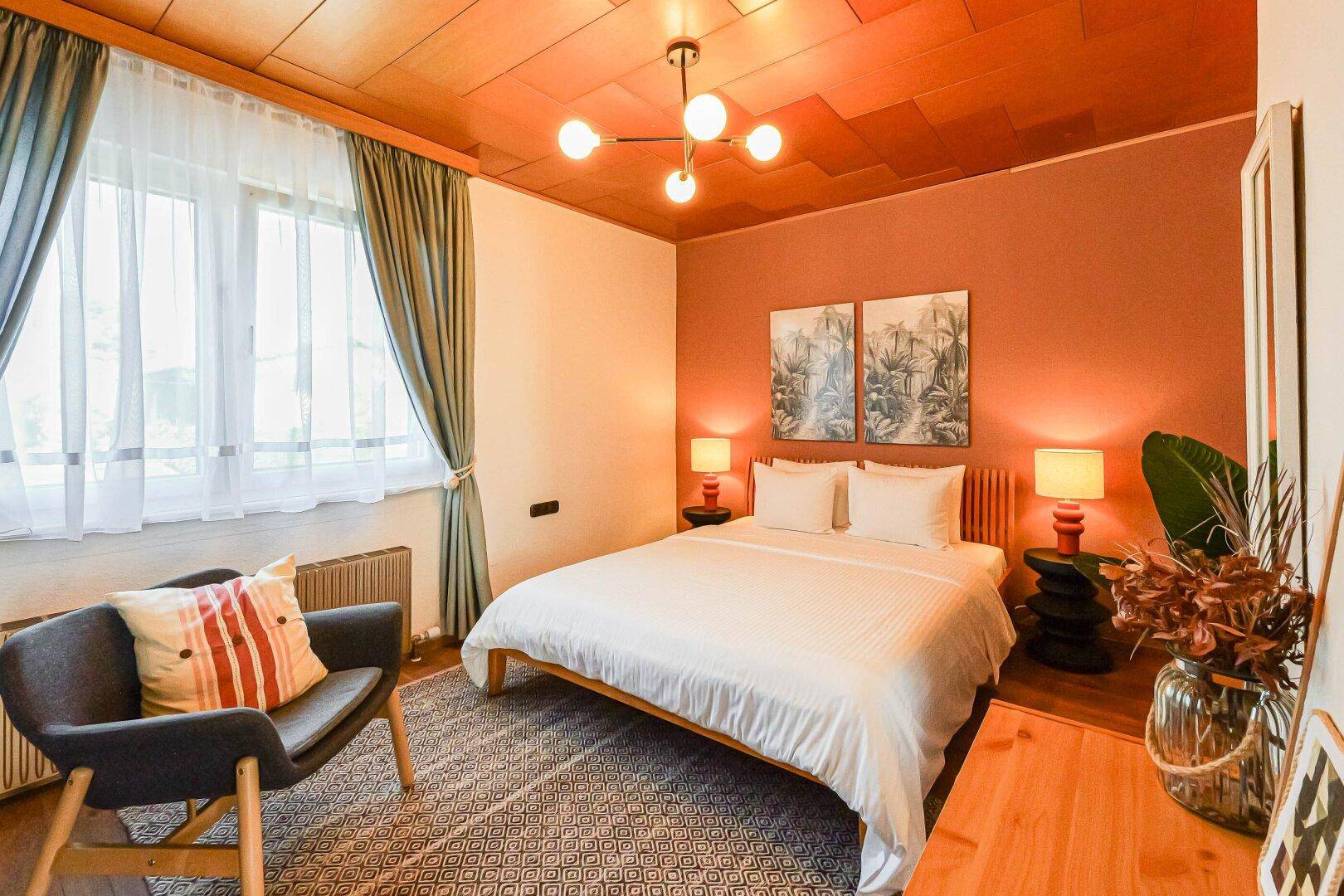 Schlafzimmer mit Holzboden, farbiger Wand und Deckenverkleidung aus Holz.