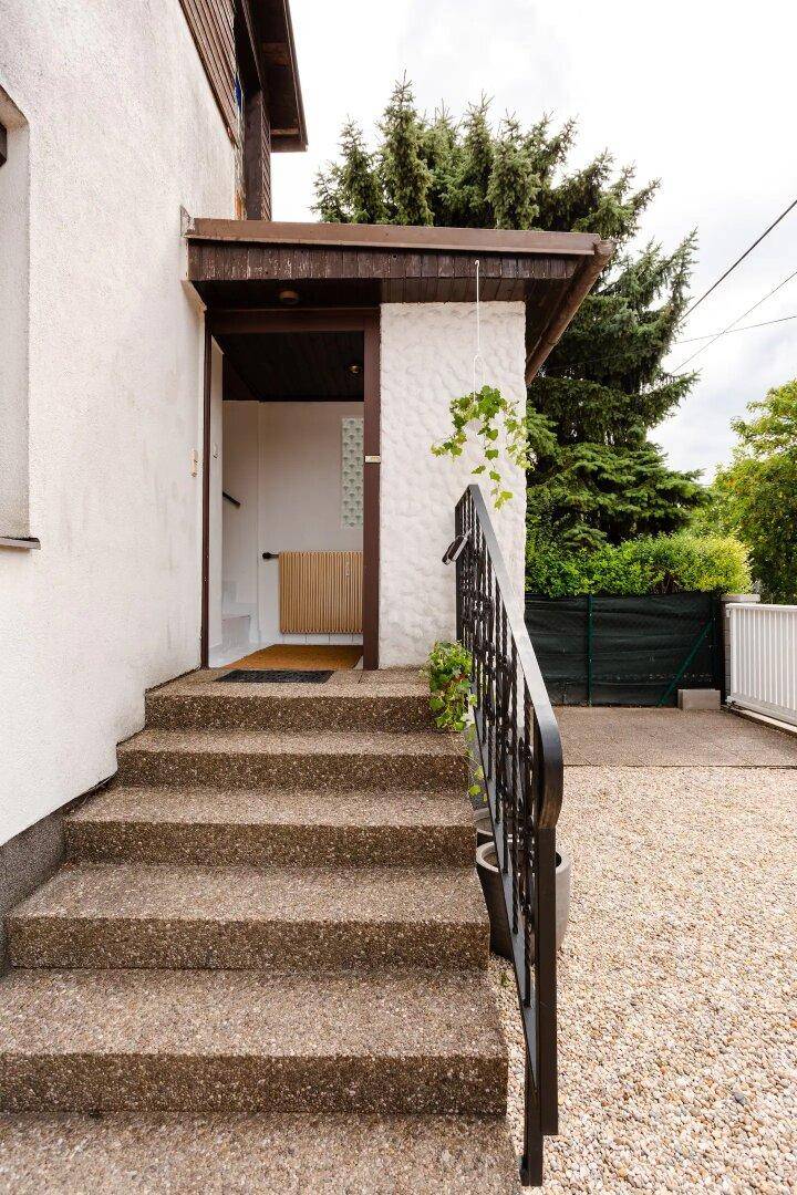 Eingangsbereich des Hauses mit Steintreppe und Kiesauffahrt.