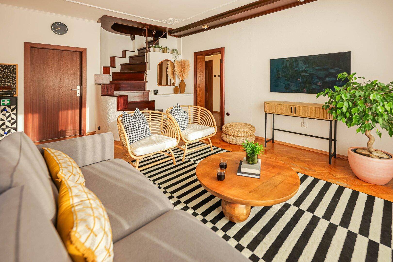 Geräumiges Wohnzimmer mit Holzparkett, bequemen Sofas und einer Holztreppe.