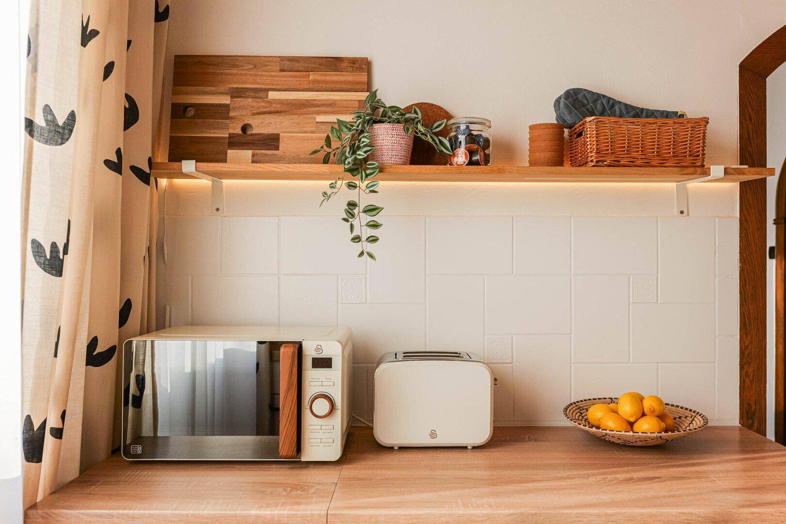 Küchenzeile mit Mikrowelle, Toaster und offener Holzablage.