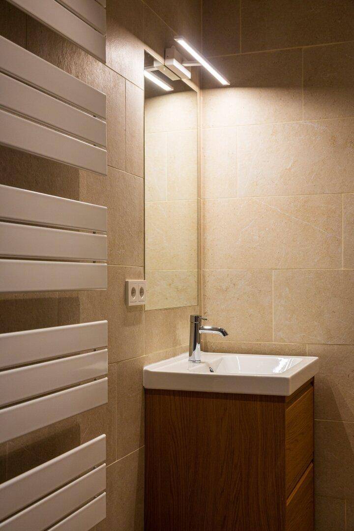 Stilvolles Badezimmer mit Einzelwaschbecken, beleuchtetem Spiegel und beheiztem Handtuchhalter.