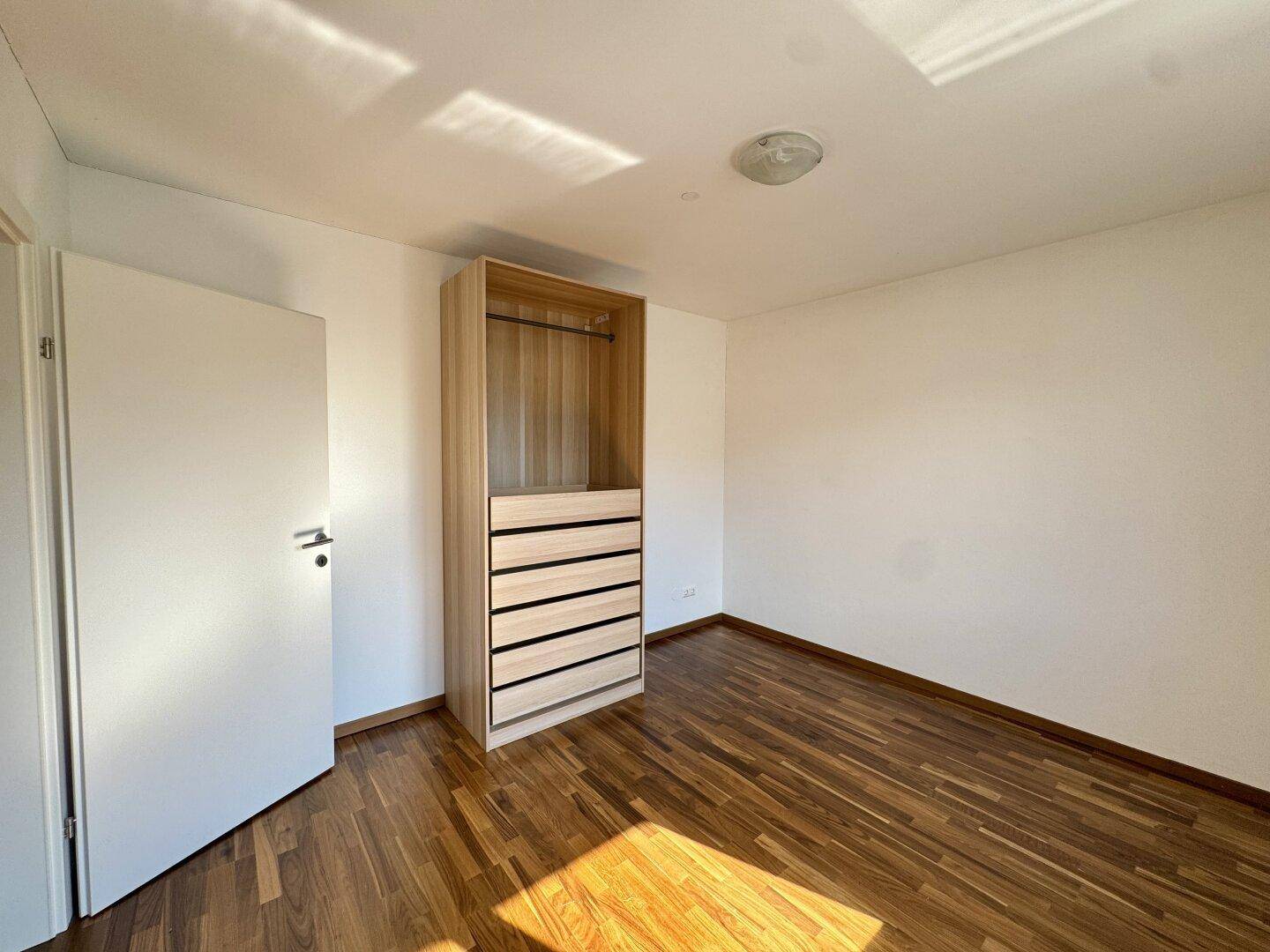 Leeres Schlafzimmer mit Holzboden und einem praktischen Einbauschrank für Kleidung.