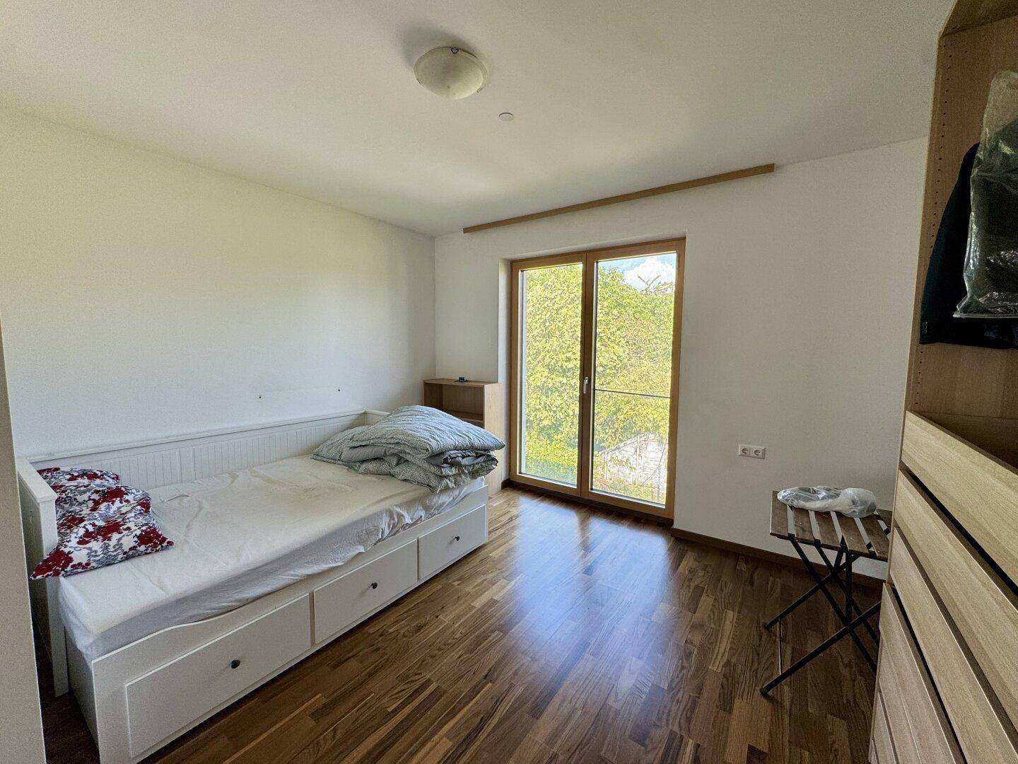 Gemütliches Schlafzimmer mit Einzelbett, Holzboden und Zugang zu einem Außenbereich.