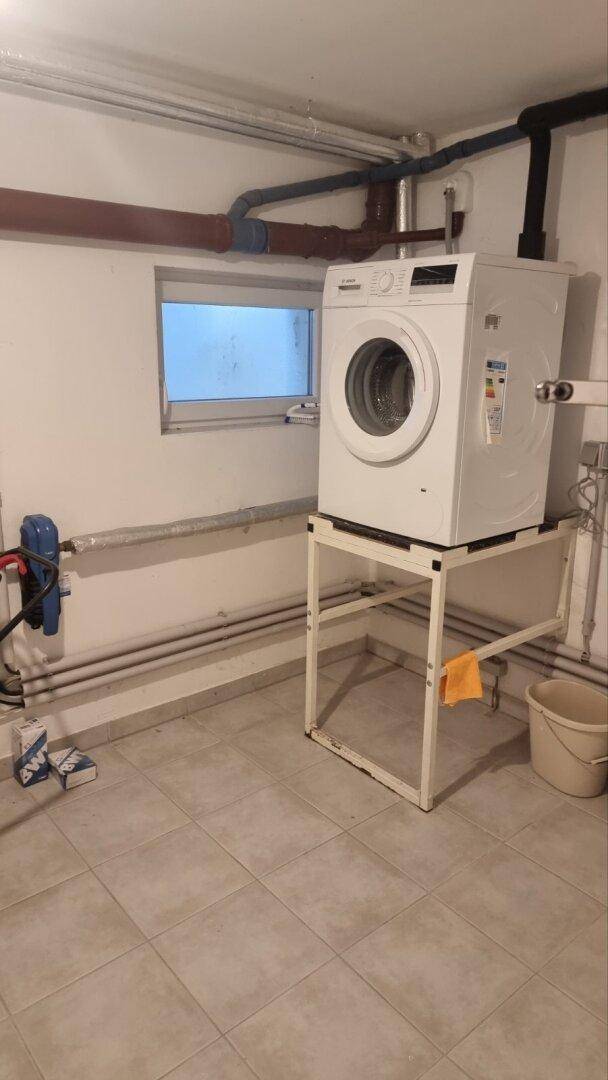Praktischer Hauswirtschaftsraum im Keller mit Waschmaschine und Fliesenboden.