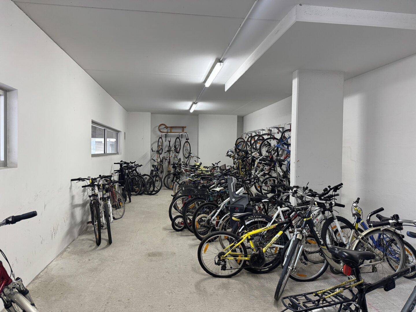 Fahrradraum mit vielen abgestellten Fahrrädern und ausreichend Platz.