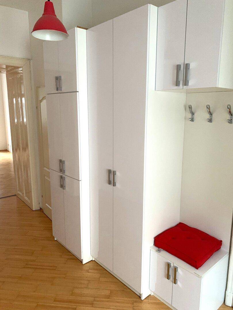 Weiße Hochglanz-Einbauschränke im Flur bieten viel Stauraum und eine praktische Garderobe.