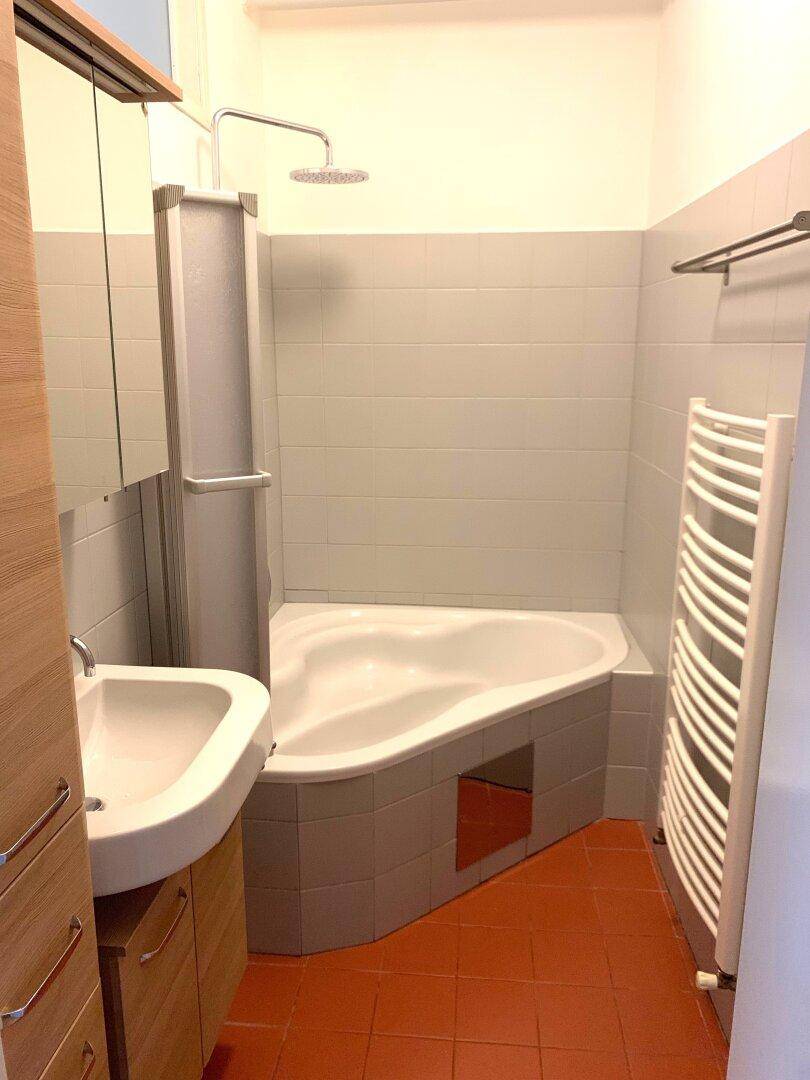 Badezimmer mit Eckbadewanne, Waschbecken, Duschvorrichtung und beheiztem Handtuchhalter.