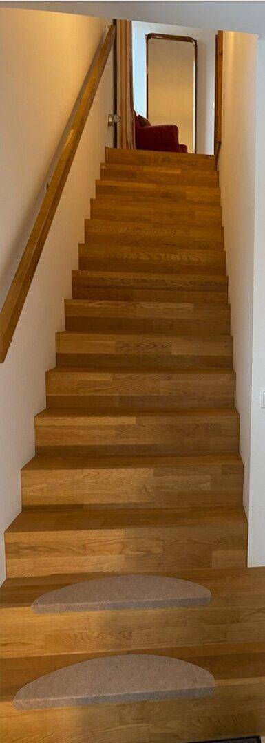 Holztreppe mit hellem Geländer, die die verschiedenen Ebenen des Hauses verbindet.