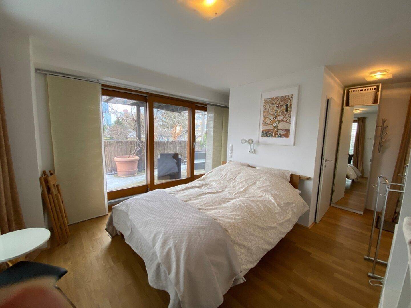 Schlafzimmer mit Holzboden, großem Bett und direktem Zugang zur Terrasse.