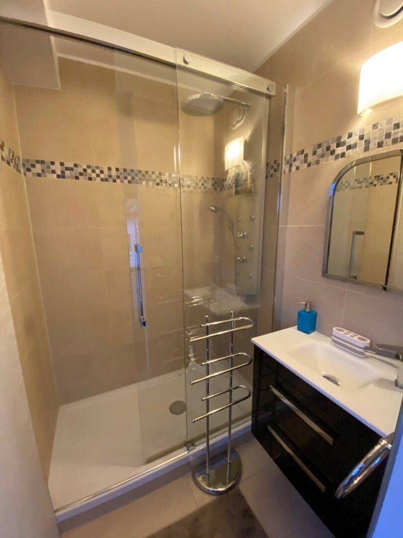 Modernes Badezimmer mit Duschkabine, beigefarbenen Fliesen und elegantem Waschtisch.
