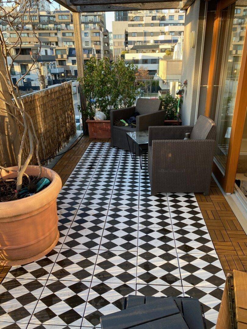 Großer Balkon mit schwarz-weiß gefliestem Boden und Sitzgelegenheiten im Freien.