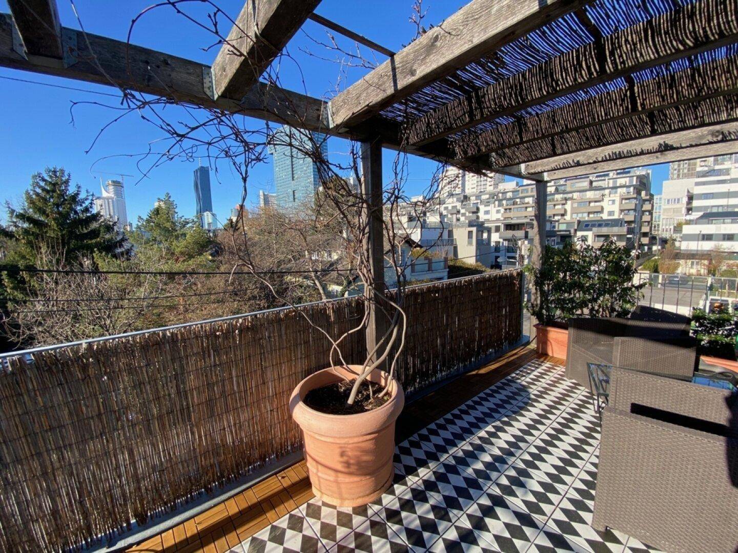 Dachterrasse mit Pergola, Pflanzen und weitem Blick über die Stadt.