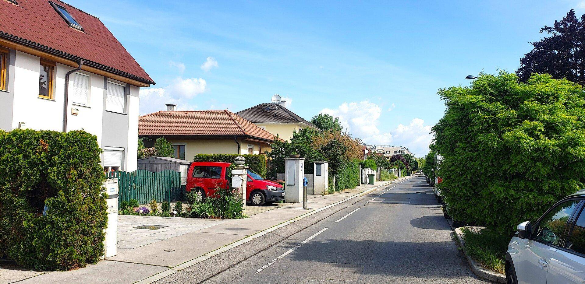 Ruhige Wohnstraße mit gepflegten Häusern und viel Grün in der Umgebung.