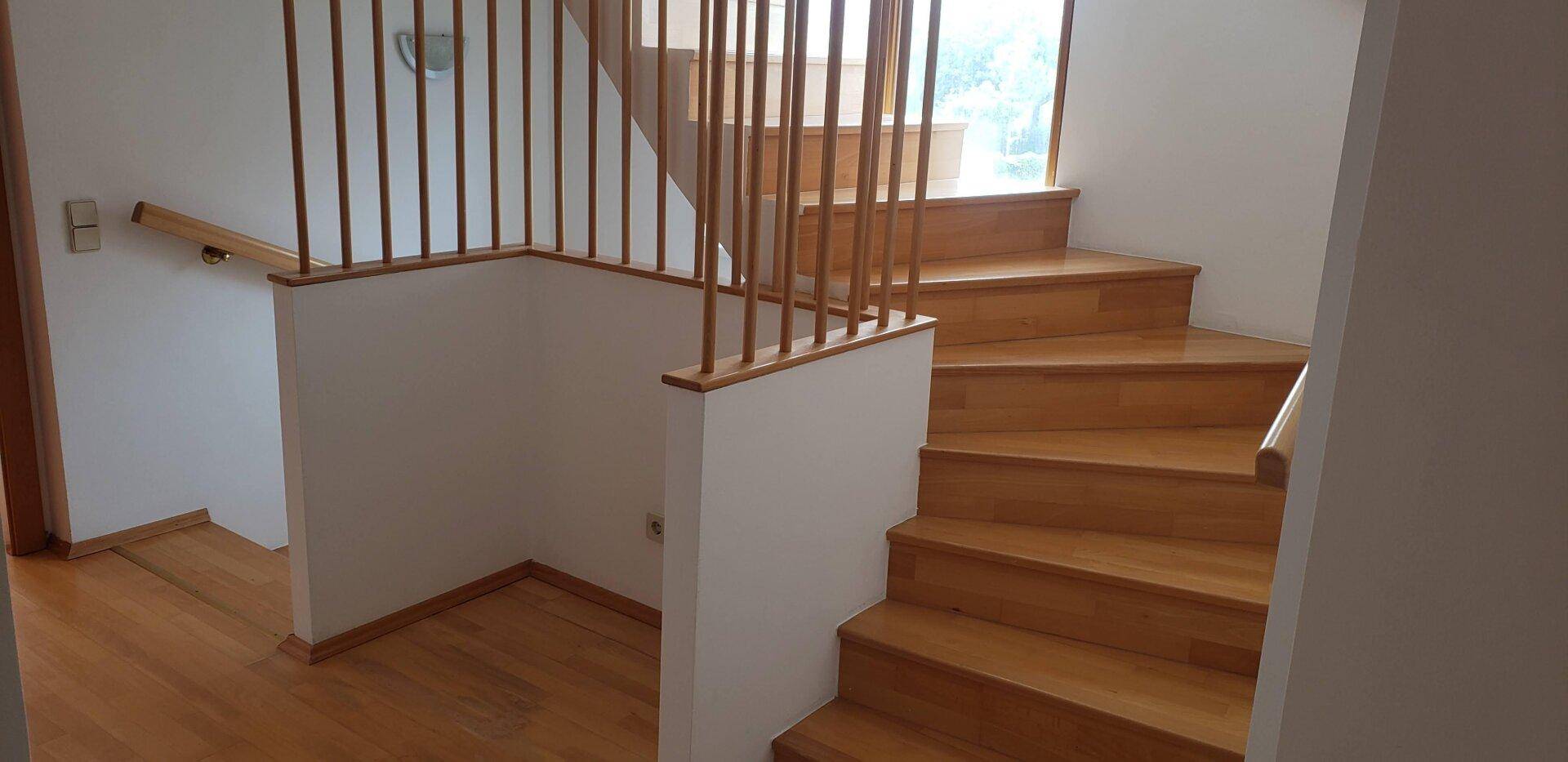 Helle Holztreppe mit Geländer, die die verschiedenen Etagen des Hauses verbindet.