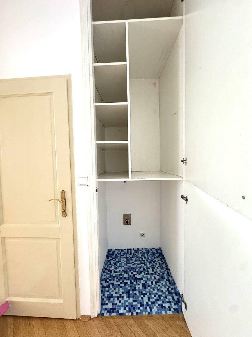 Praktischer Einbauschrank mit Regalen und Anschluss für eine Waschmaschine.