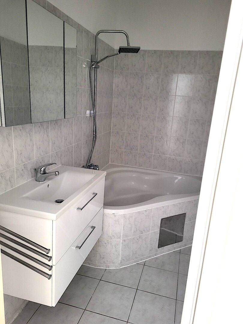 Gefliestes Badezimmer mit Eckbadewanne, Duschfunktion und modernem Waschtisch.