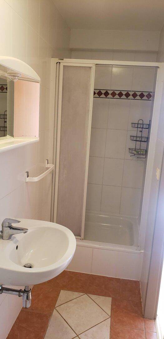 Badezimmer mit Duschkabine, Einzelwaschbecken und Spiegelschrank, praktisch gefliest.