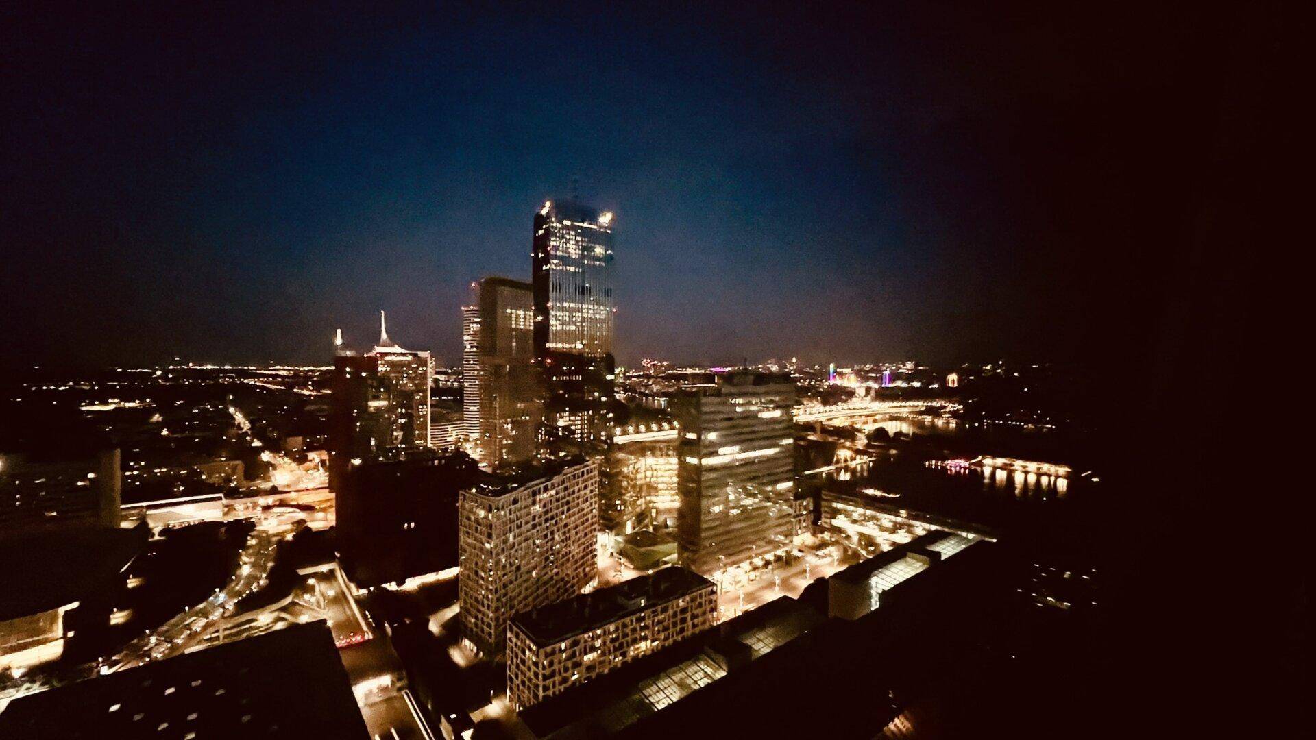 Beeindruckender nächtlicher Panoramablick auf die beleuchtete Stadt mit Hochhäusern und Brücken.