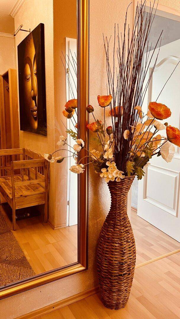 Heller Flur mit großem Spiegel und dekorativer Vase mit Blumen.