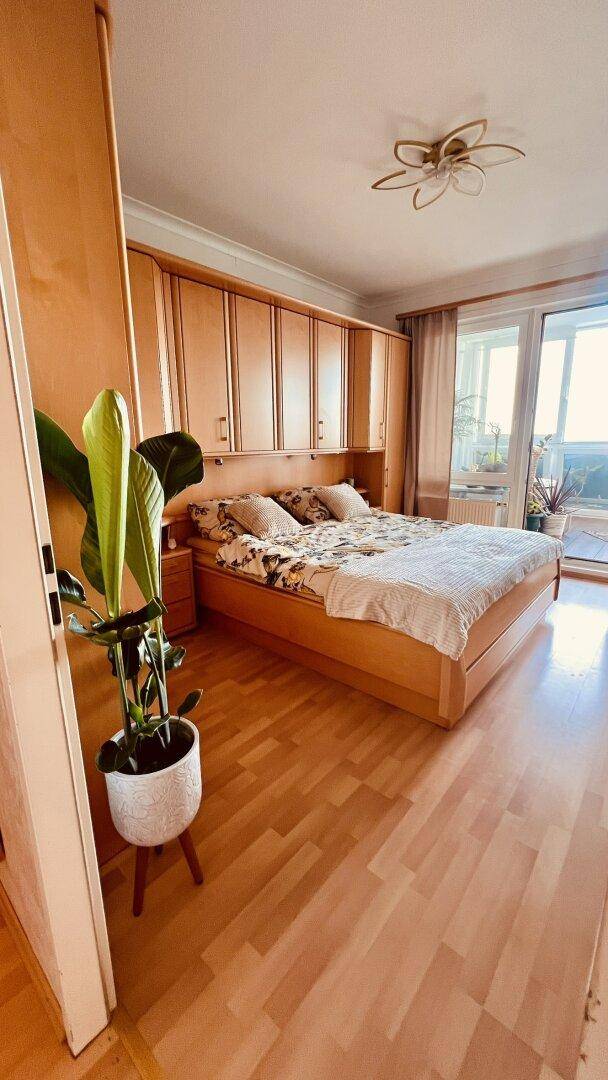 Helles Schlafzimmer mit Holzbett, integrierten Schränken und Blick nach draußen.