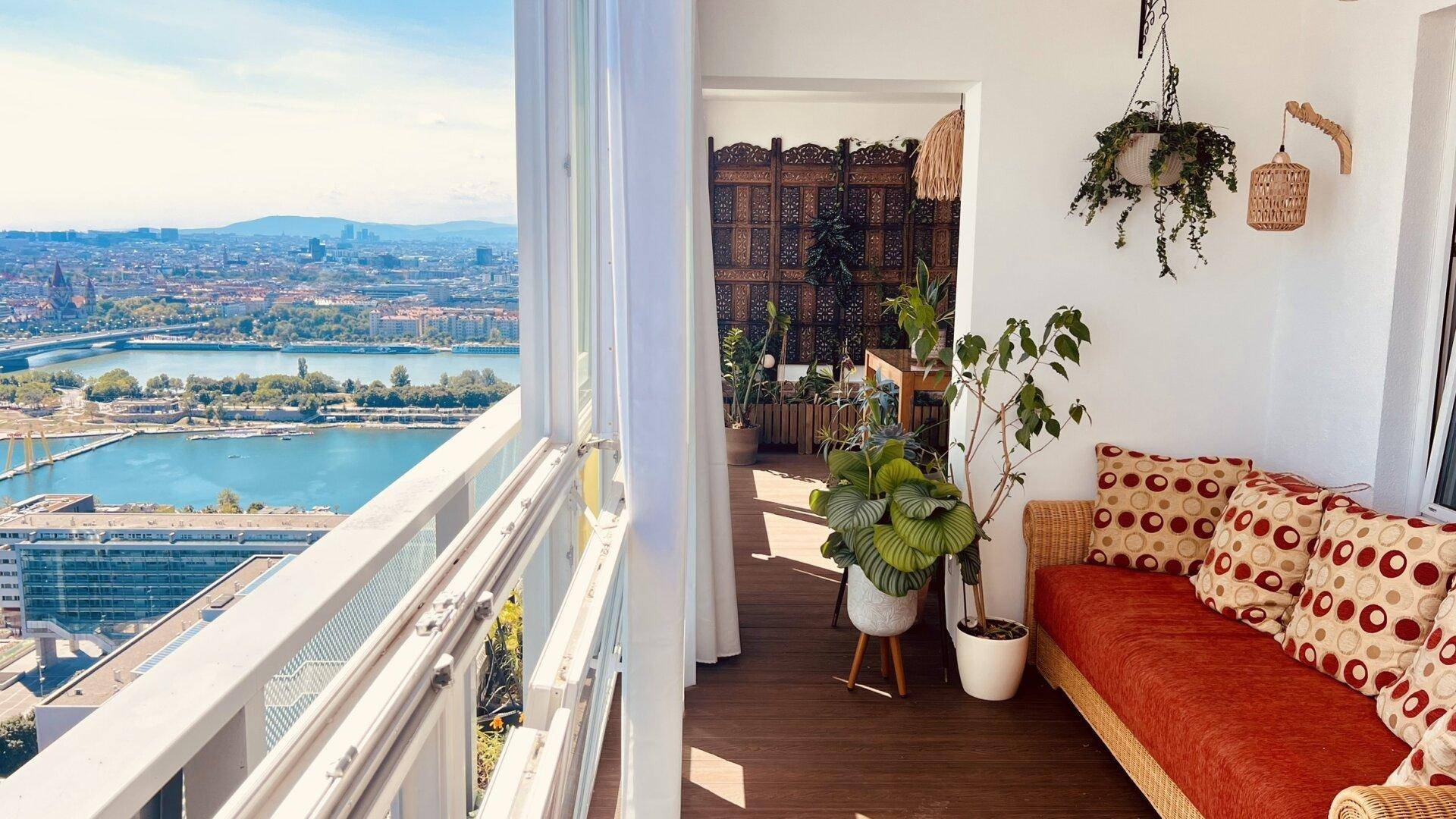 Sonniger verglaster Balkon mit bequemer Sitzbank, Pflanzen und beeindruckendem Stadtpanorama.