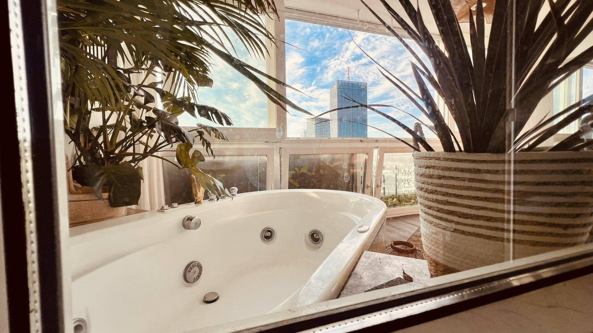 Luxuriöses Badezimmer mit Whirlpool und Panoramablick auf die Stadt durch große Fenster.