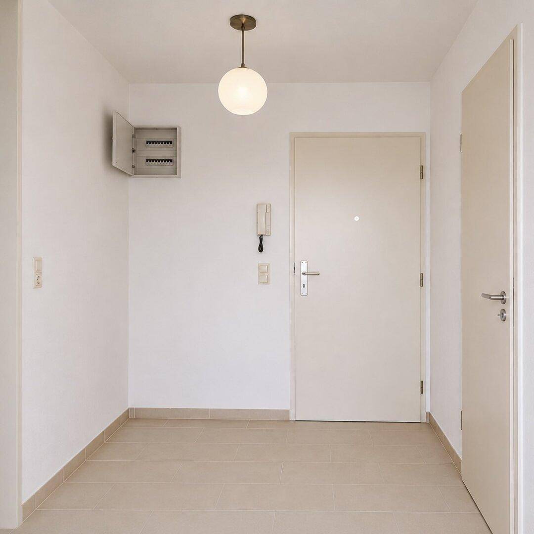 Eingangsbereich mit Haustür, Sicherungskasten und Gegensprechanlage, hell gefliest.